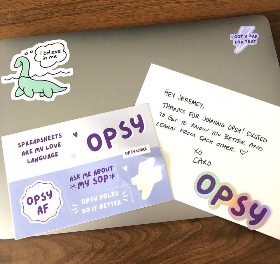 Opsy sticker sheet and thank you note from Caro on top of a member's laptop